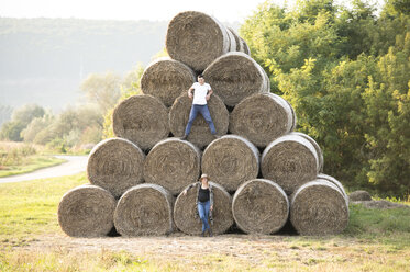 Expectant parents standing at bales of straw - HAPF01087