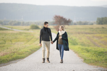 Glückliche werdende Eltern beim Spaziergang in ländlicher Landschaft - HAPF01099