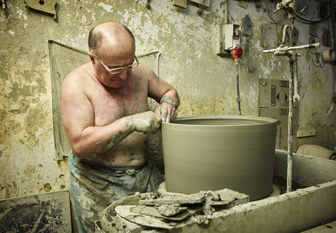 Töpfer in der Werkstatt bei der Arbeit an einer großen Terrakotta-Vase, lizenzfreies Stockfoto