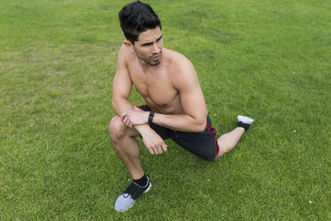 Athlet mit nacktem Oberkörper beim Dehnen im Gras - BOYF00655