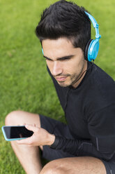 Athlete sitting in grass listening to music - BOYF00662