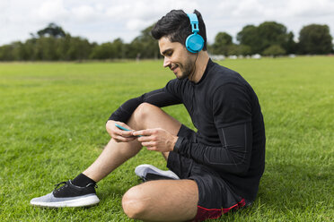 Sportler sitzt im Gras und hört Musik - BOYF00663