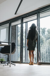 Frau mit langen grauen Haaren schaut aus dem Fenster - KNSF00441