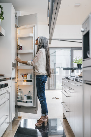Woman in kitchen looking in fridge stock photo
