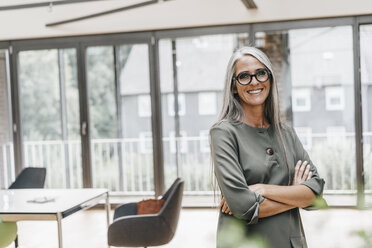 Portrait of smiling woman with long grey hair in office - KNSF00448