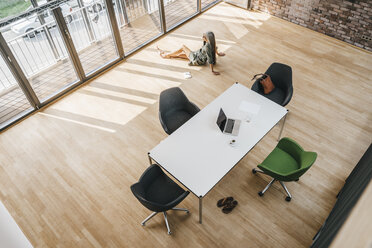 Top view of woman sitting on the floor in boardroom - KNSF00467