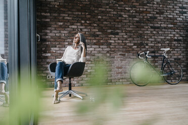 Woman with long grey hair sitting on chair at the window - KNSF00478