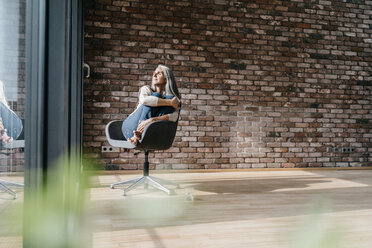 Woman with long grey hair sitting on chair at the window - KNSF00480