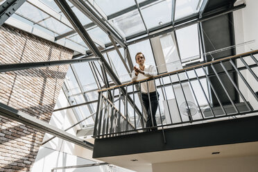 Businessman standing on upper floor in office - KNSF00502