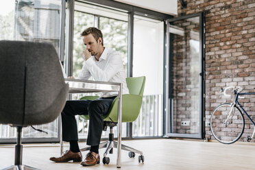 Geschäftsmann mit Laptop im Büro - KNSF00507