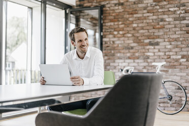 Smiling businessman using laptop in office - KNSF00508