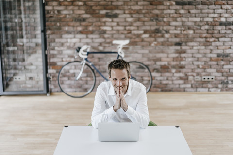 Lächelnder Geschäftsmann mit Laptop im Büro, lizenzfreies Stockfoto