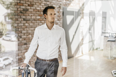 Businessman with bicycle in office - KNSF00515