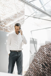 Businessman in office on cell phone - KNSF00519