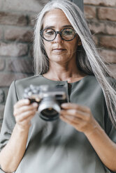 Frau mit langen grauen Haaren hält Kamera - KNSF00524