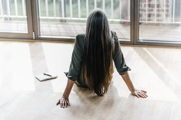 Woman sitting on the floor looking out of window - KNSF00535