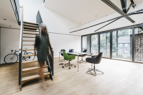 Woman on the move on stairs in office stock photo