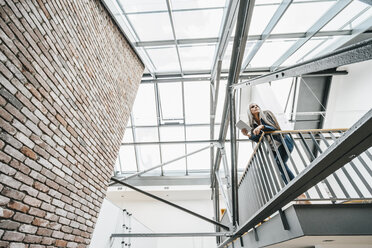 Frau mit langen grauen Haaren in einem Loft stehend - KNSF00558