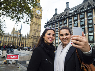 Großbritannien, London, zwei glückliche Freunde machen ein Selfie mit Smartphone vor dem Big Ben - AMF05055