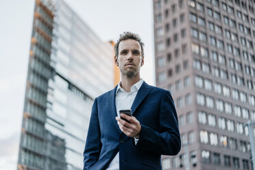 Germany, Berlin, portrait of businessman with smartphone - KNSF00620