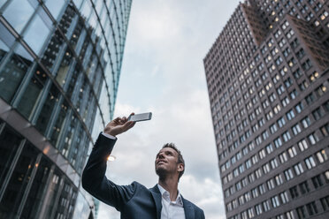 Deutschland, Berlin, Geschäftsmann macht Selfie mit Smartphone - KNSF00631