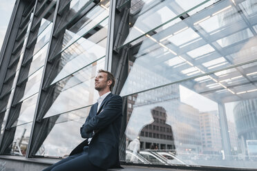 Germany, Berlin, businessman sitting at Potzdamer Platz watching something - KNSF00635