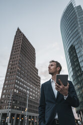 Germany, Berlin, businessman with tablet standing at Potsdamer Platz - KNSF00640