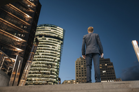 Deutschland, Berlin, Potsdamer Platz, Rückansicht eines Geschäftsmannes bei Nacht, lizenzfreies Stockfoto