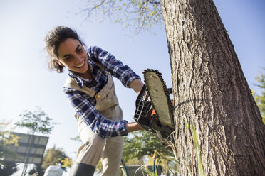 Woman on farm cuttiing tree with chain saw - ABZF01489