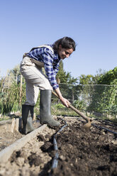 Frau arbeitet auf dem Bauernhof, bereitet Gemüsebeet mit Hacke vor - ABZF01493
