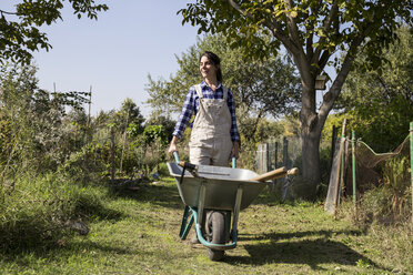 Woman working on farm pushing wheel barrow - ABZF01513