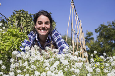 Glückliche Frau bei der Arbeit auf dem Bauernhof, die Blumen untersucht - ABZF01515