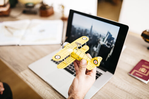 Mann hält Spielzeugflugzeug vor einem Laptop - JRFF01041