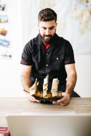 Junger Mann betrachtet ein Schiffsmodell, lizenzfreies Stockfoto