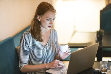 Portrait of woman sitting in a coffee shop using laptop - TAMF00786