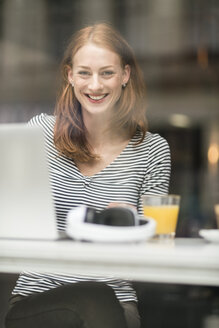 Porträt einer glücklichen Frau, die in einem Café sitzt - TAMF00790