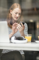 Portrait of woman text messaging in a coffee shop - TAMF00791