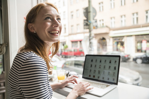 Lächelnde Frau mit Laptop in einem Café, lizenzfreies Stockfoto