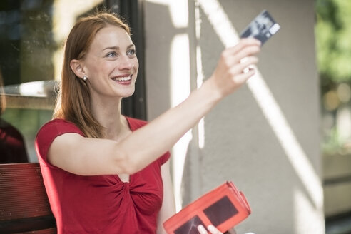 Porträt einer lächelnden Frau, die mit einer Kreditkarte bezahlt - TAMF00803