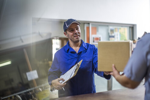 Delivery man handing over cardboard box - ZEF11610