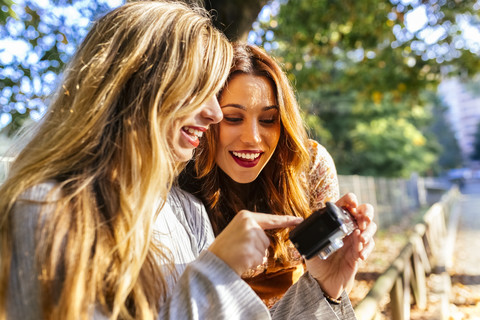 Zwei junge Frauen mit Kamera in einem Park im Herbst, lizenzfreies Stockfoto