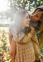 Two playful young women in a park in autumn - MGOF02599