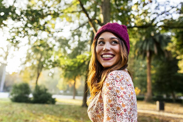 Glückliche junge Frau mit Wollmütze in einem Park im Herbst - MGOF02604