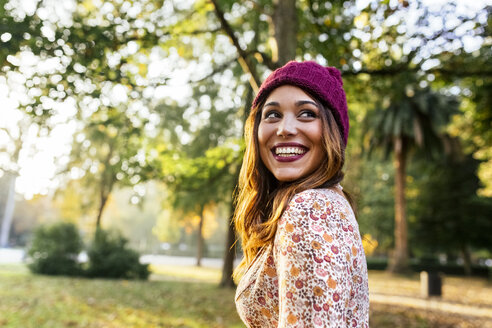 Happy young woman wearing wooly hat in a park in autumn - MGOF02604