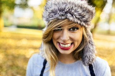 Portrait of smiling young woman wearing fur hat - MGOF02606