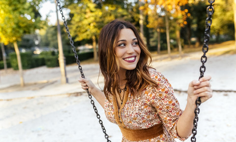 Smiling young woman on a swing stock photo