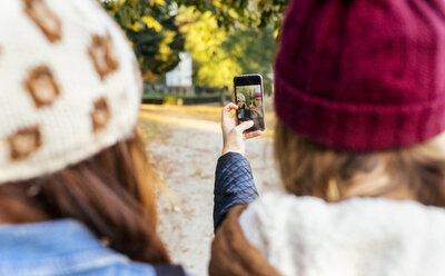 Zwei junge Frauen machen ein Selfie in einem Park im Herbst - MGOF02619