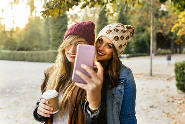 Zwei lächelnde junge Frauen machen ein Selfie in einem Park im Herbst - MGOF02620