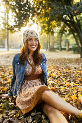 Smiling young woman in a park in autumn - MGOF02623