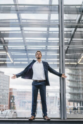 Businessman standing in front of glass pane - KNSF00665